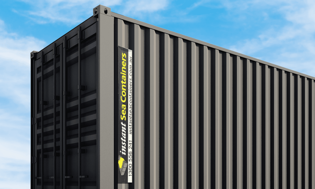 Close-up view of a tall, dark gray shipping container of Instant Sea Containers, set against a clear blue sky.