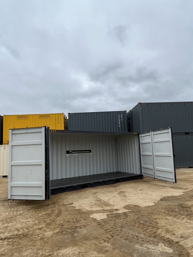 Open black 20’HC Side Opening Container on a dirt lot under a cloudy sky.