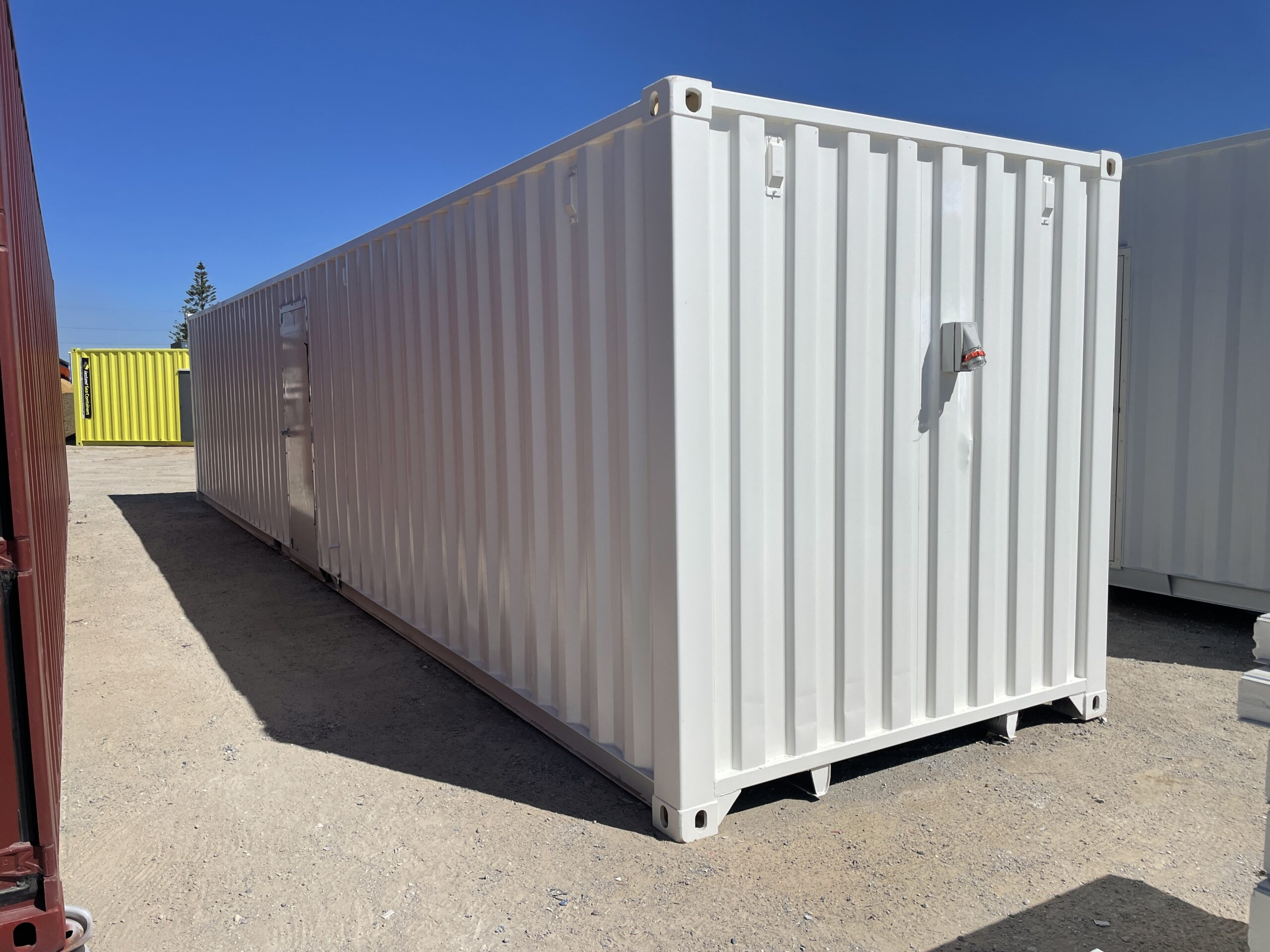 White shipping container on a gravel lot with a blue sky in the background.