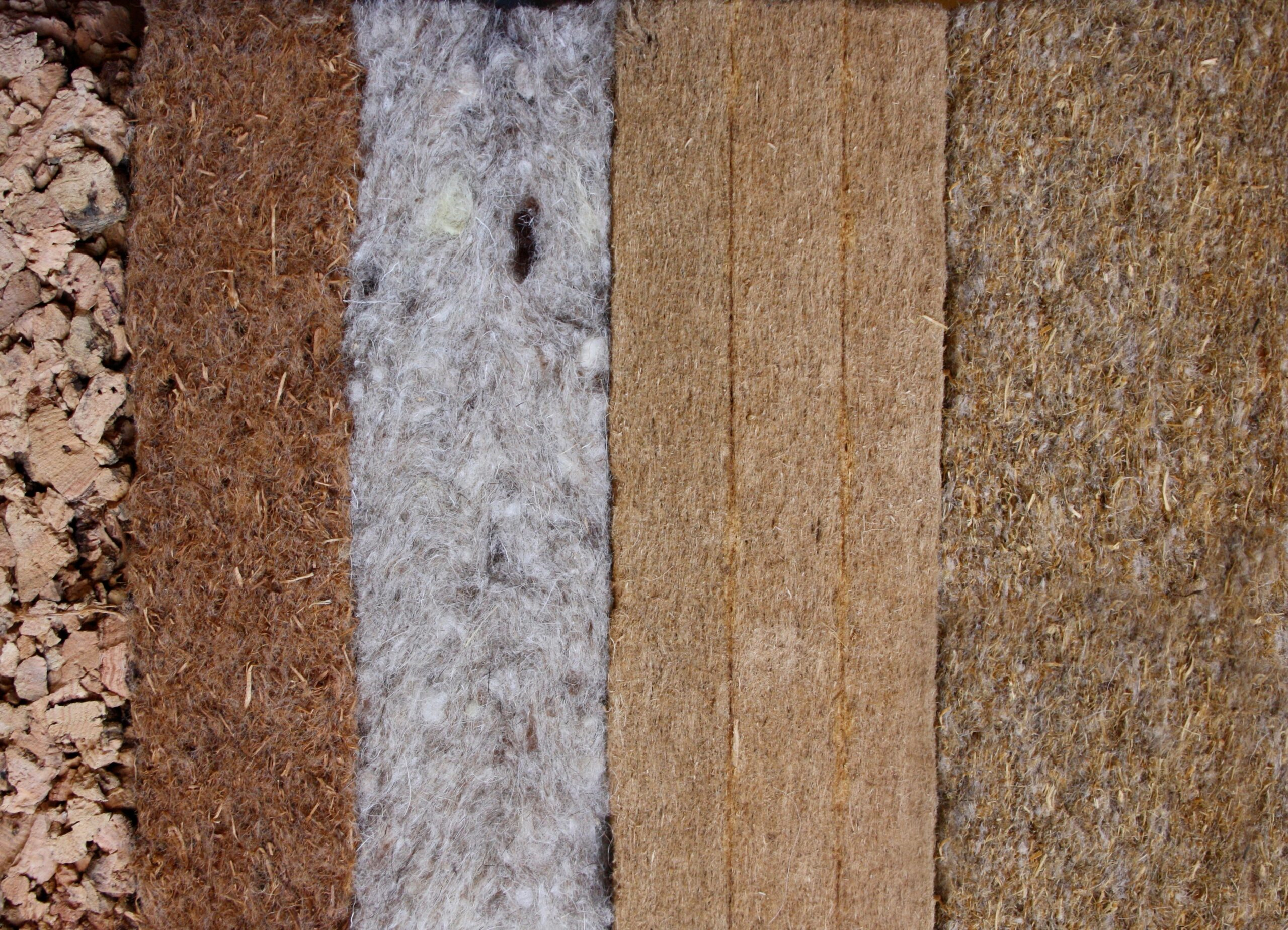 Top view of various types of eco-friendly insulation materials including wool, cotton, and cellulose.