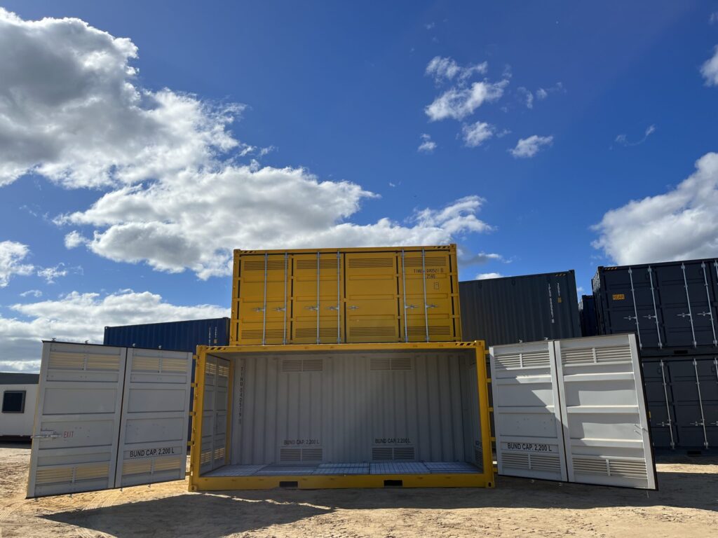 Bright yellow shipping containers with safety labels in an outdoor storage area.