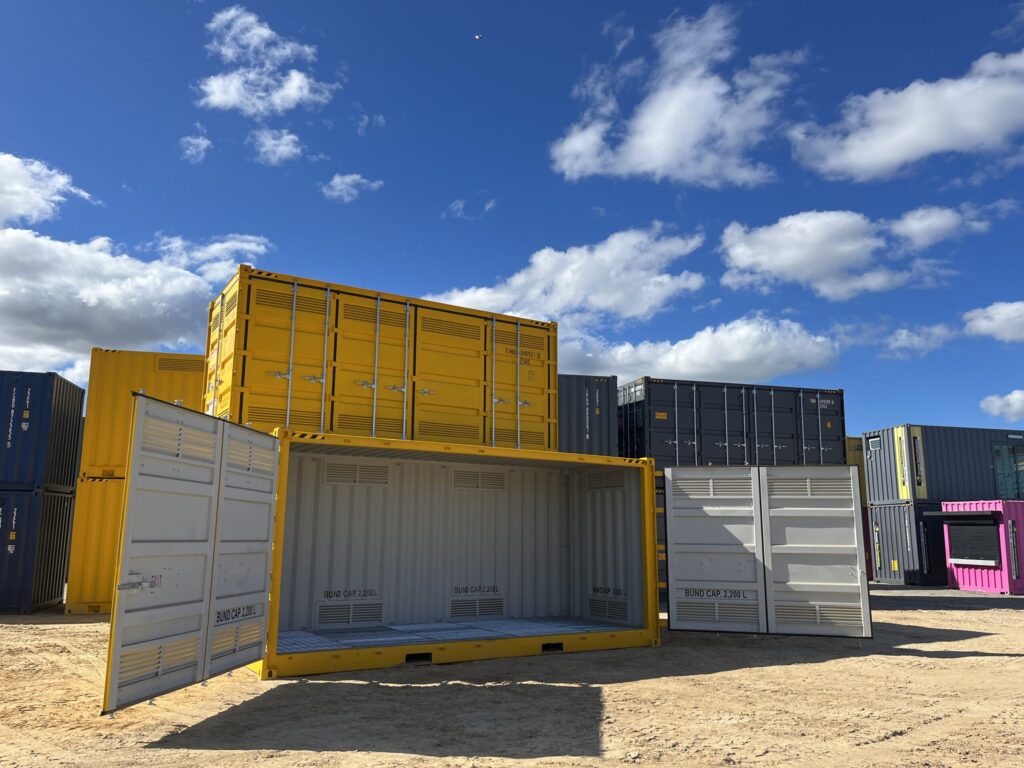 Cluster of yellow containers, some with open doors, set against a clear sky.