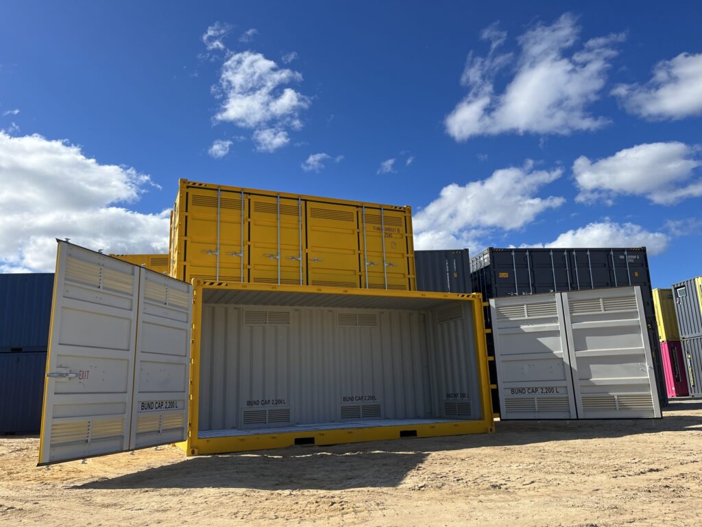 Open yellow shipping container with bund capacity labels, stacked containers in