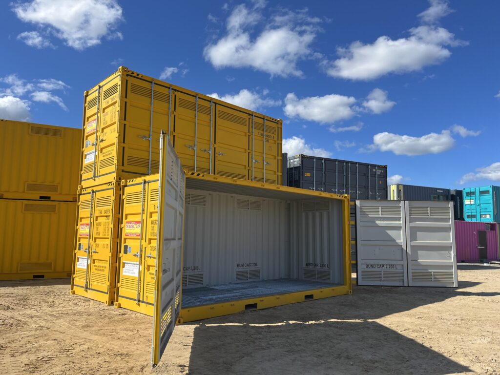 Partially open yellow container on sandy ground, surrounded by other storage uni