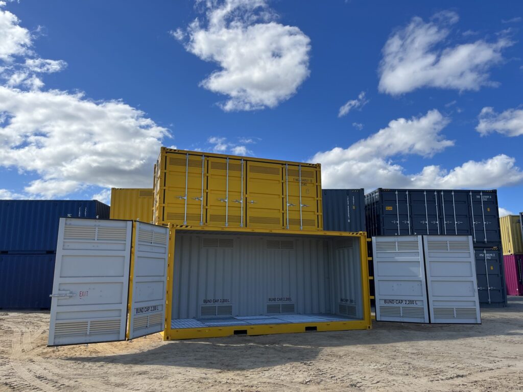 Stacked yellow containers in a storage yard under a blue sky, one container open