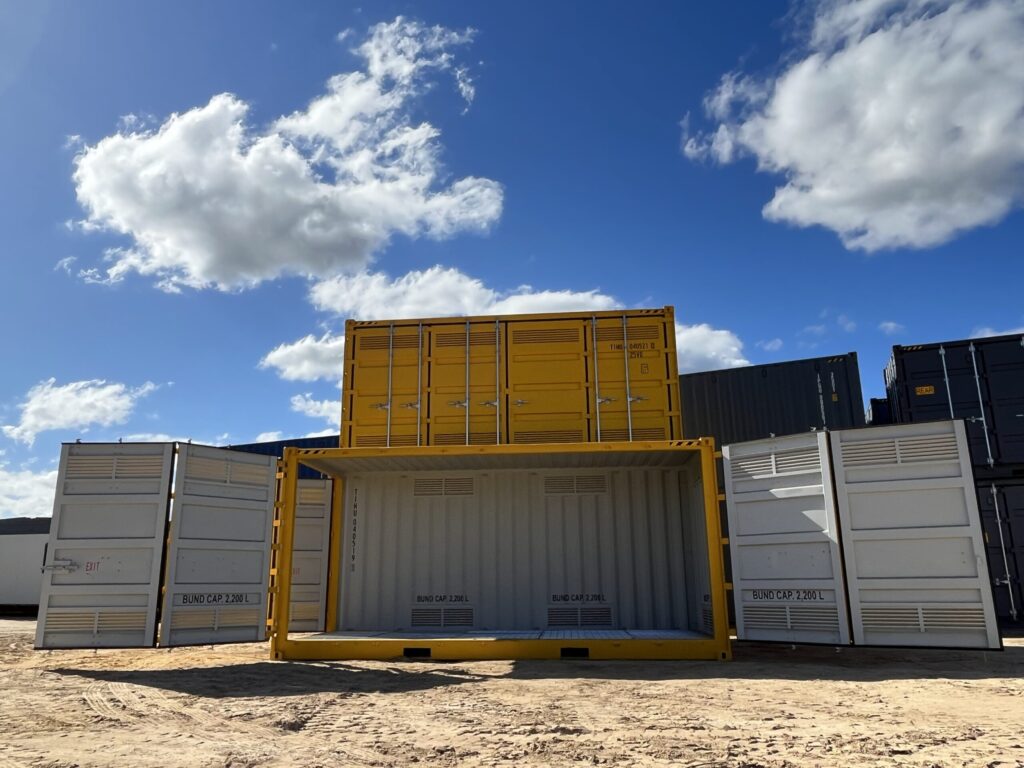 Stacked yellow containers in an outdoor yard, one unit open to display interior