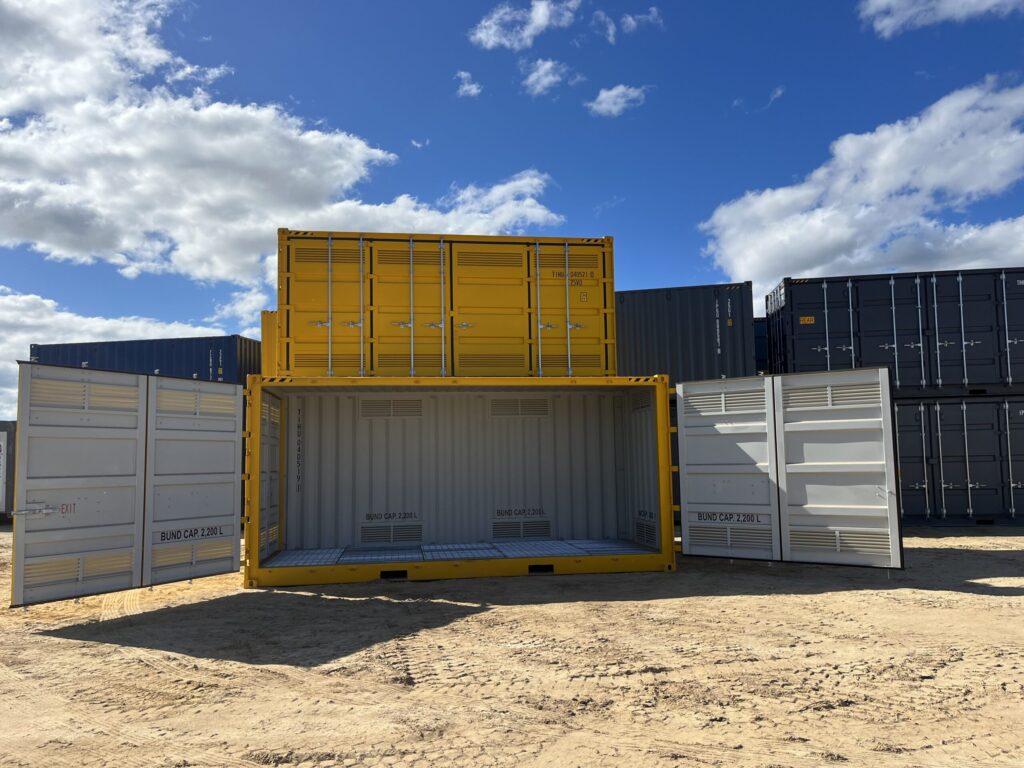 Yellow and gray industrial containers placed on sandy ground in a storage facili