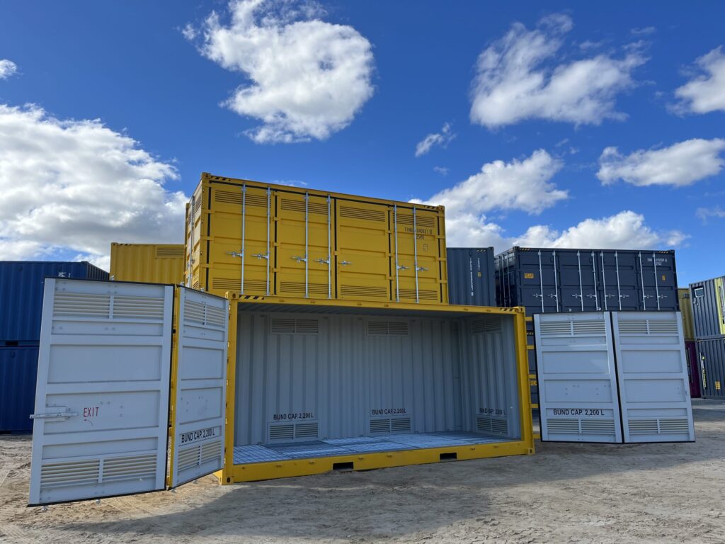 Yellow and gray shipping containers arranged in a spacious yard on a sunny day.