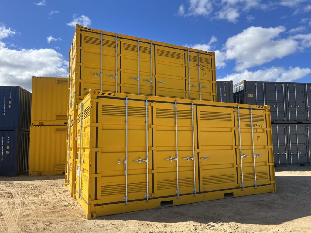 Yellow shipping containers with ventilation panels stacked in a storage yard.