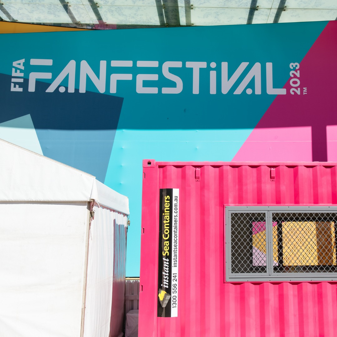 Close-up of colorful FIFA Fan Festival signage and pink shipping container at the event in 2023.