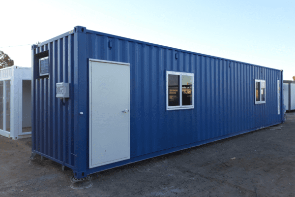 Exterior view of a blue shipping container converted into a portable office with a white door and windows.