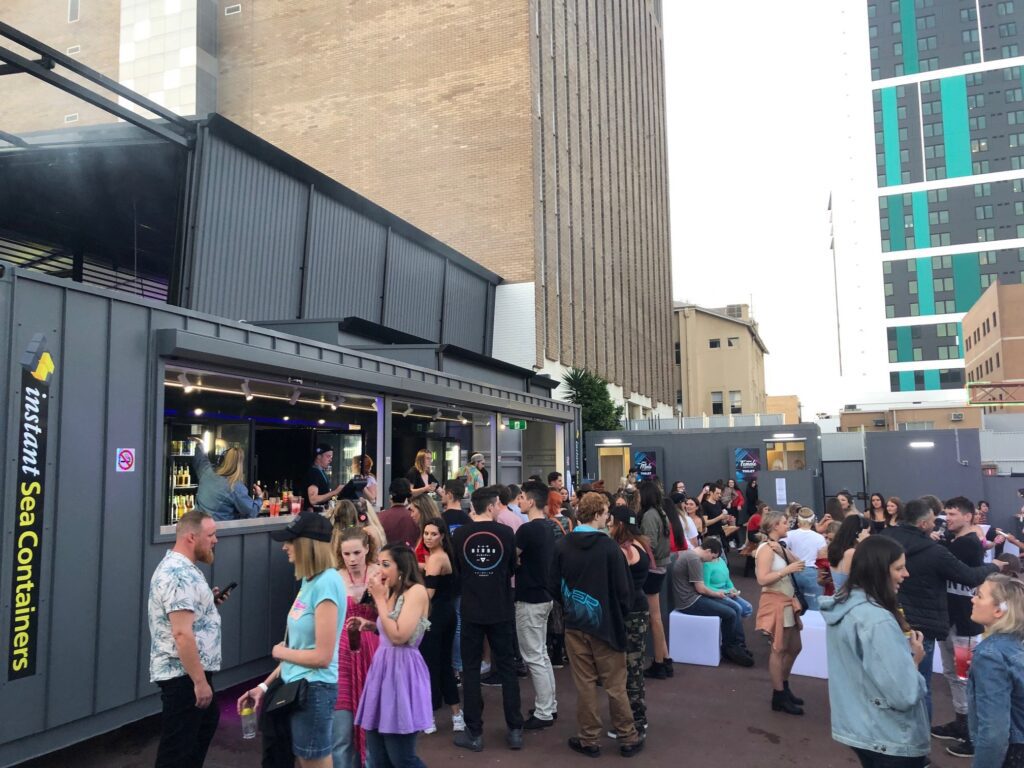 Outdoor gathering of people at Shipping Container Bars in an urban setting