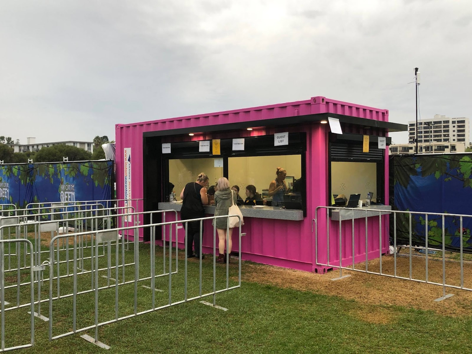 Bright pink shipping container converted into an outdoor event ticket booth.