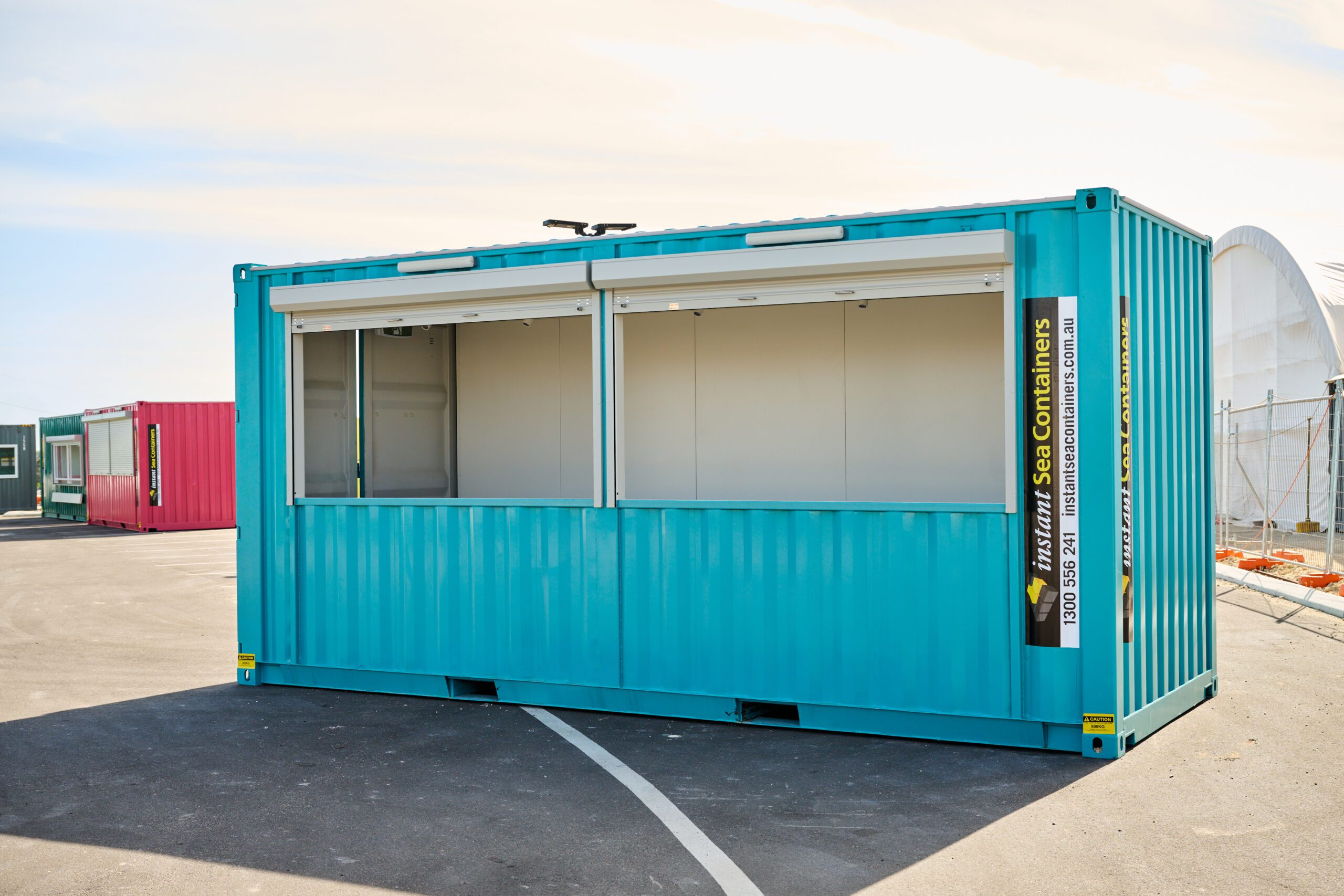 Shipping Container Bar, painted in an attractive teal color, featuring large open windows suitable for serving customers or for display purposes.