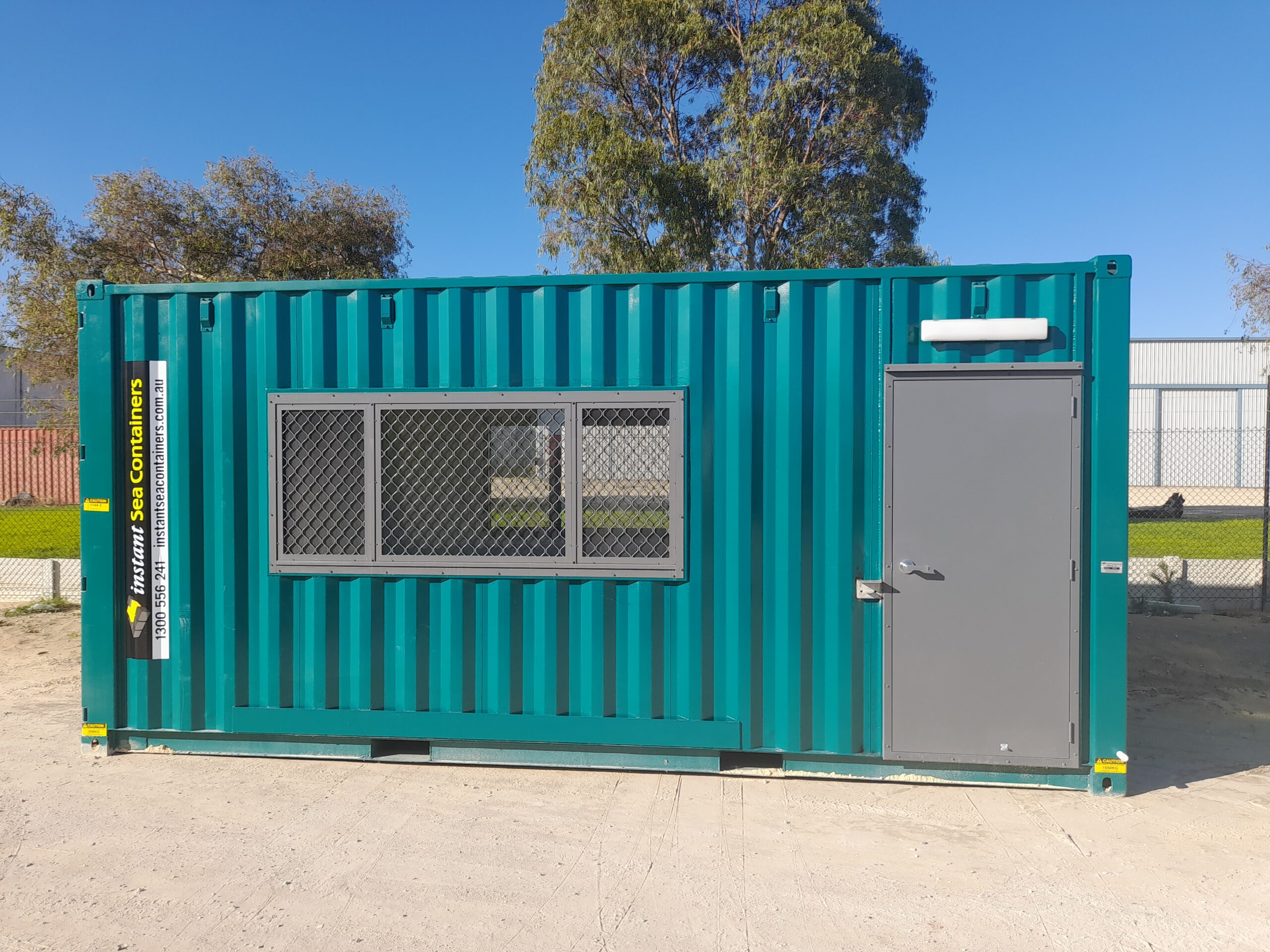 Shipping Container Event Office in a striking teal color, equipped with a large mesh window and a secure side door