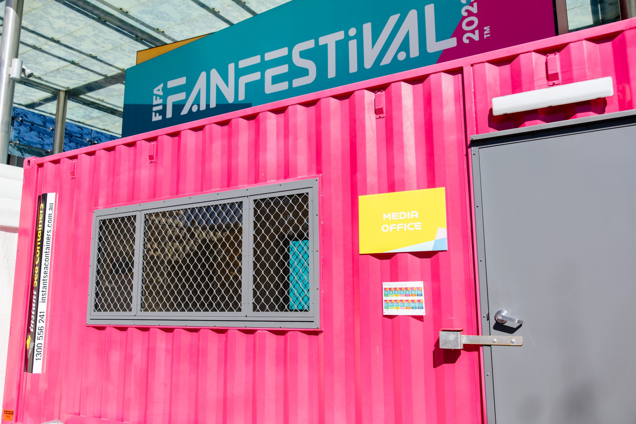 Media Office at FIFA Fan Festival 2023 in a bright pink container with event signage