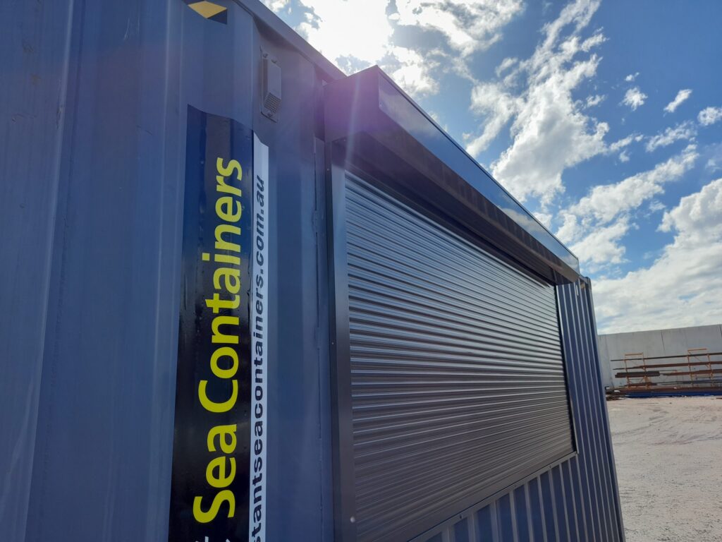 Close-up of blue shipping container kitchen exterior with Instant Sea Containers branding and a closed roller shutter.