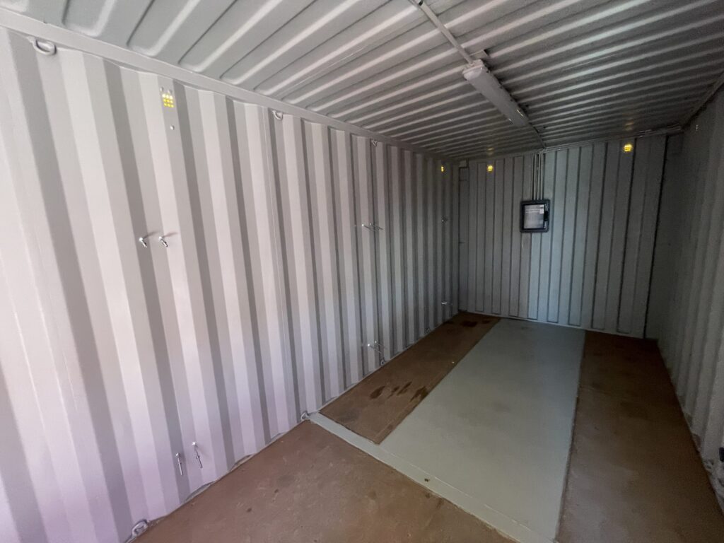 Interior of empty gray Shipping Container Storages with visible wiring along walls.