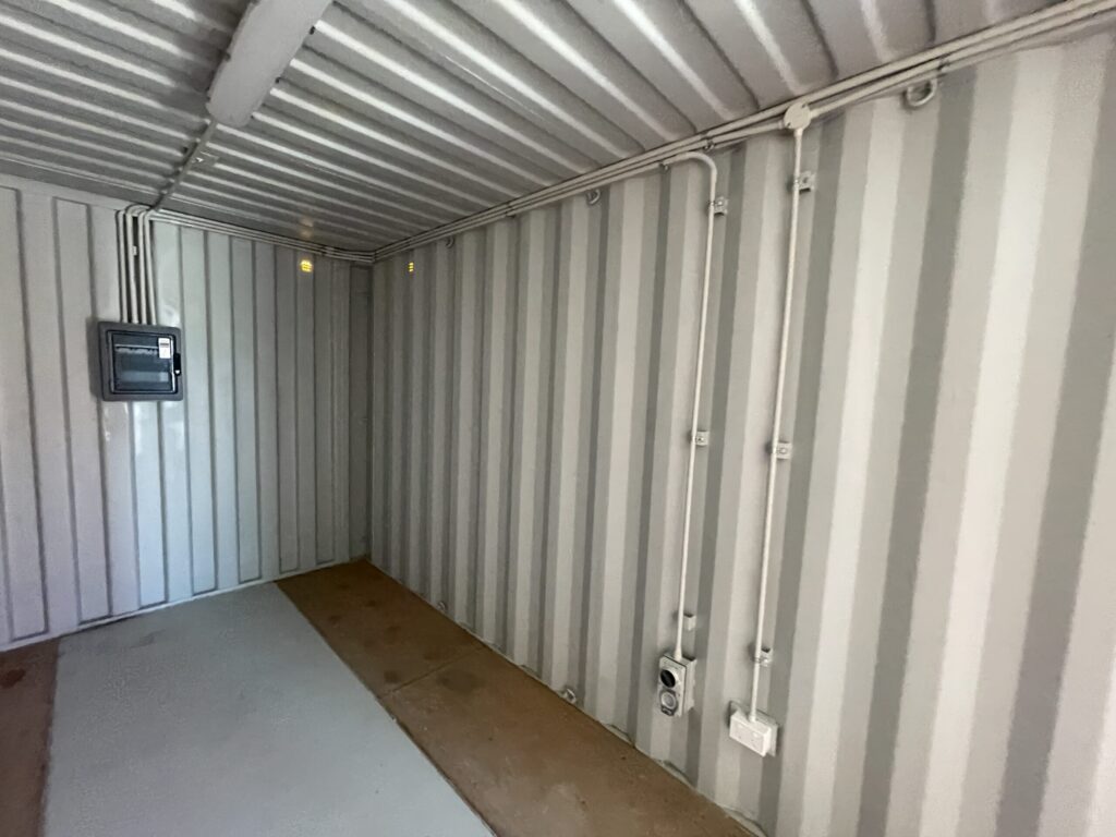 Interior of empty gray Shipping Containers for Events with visible wiring on walls.