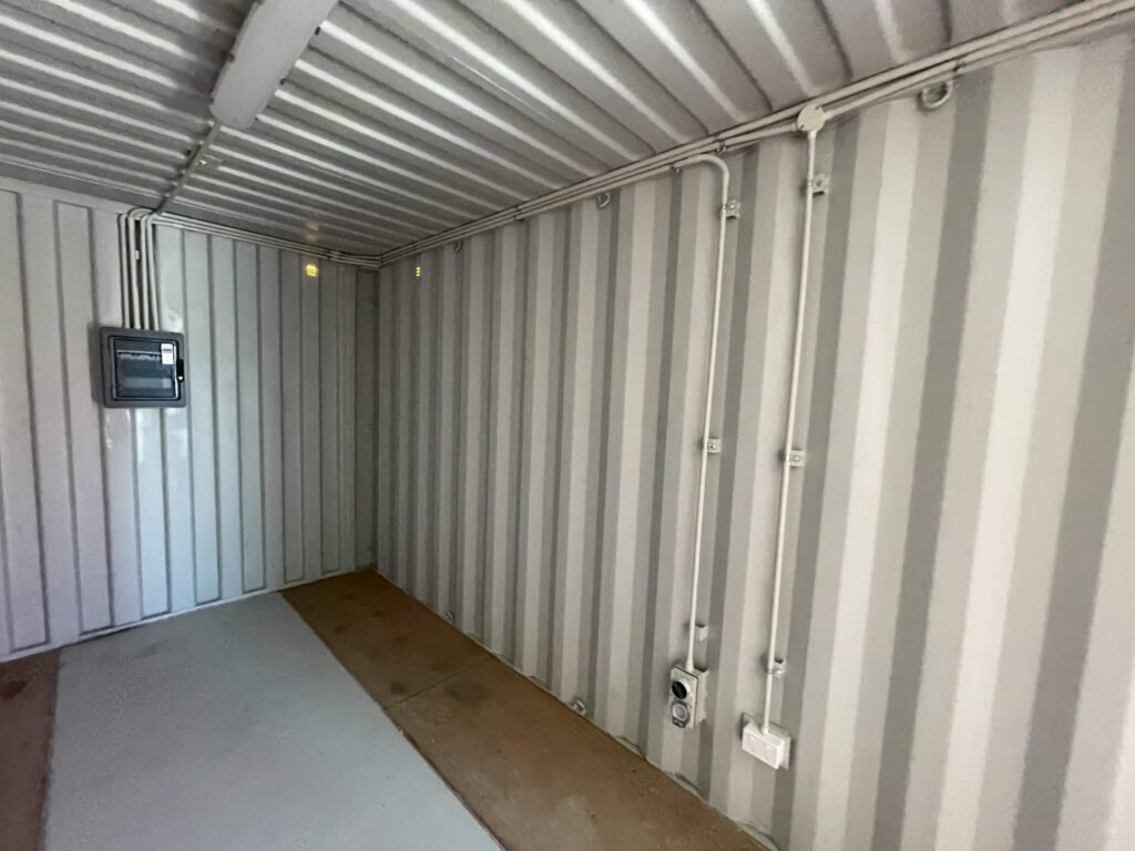 Interior of gray Shipping Container Storages with wall-mounted wiring and outlets.