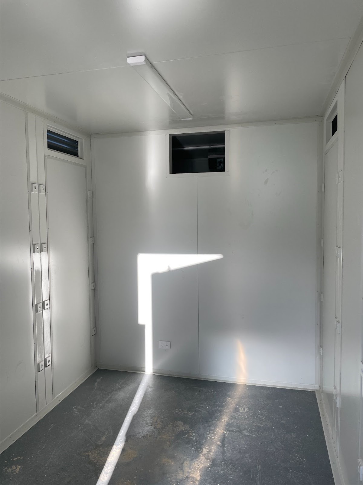 Empty interior of a white Solar Battery Containers with a window and ceiling light.