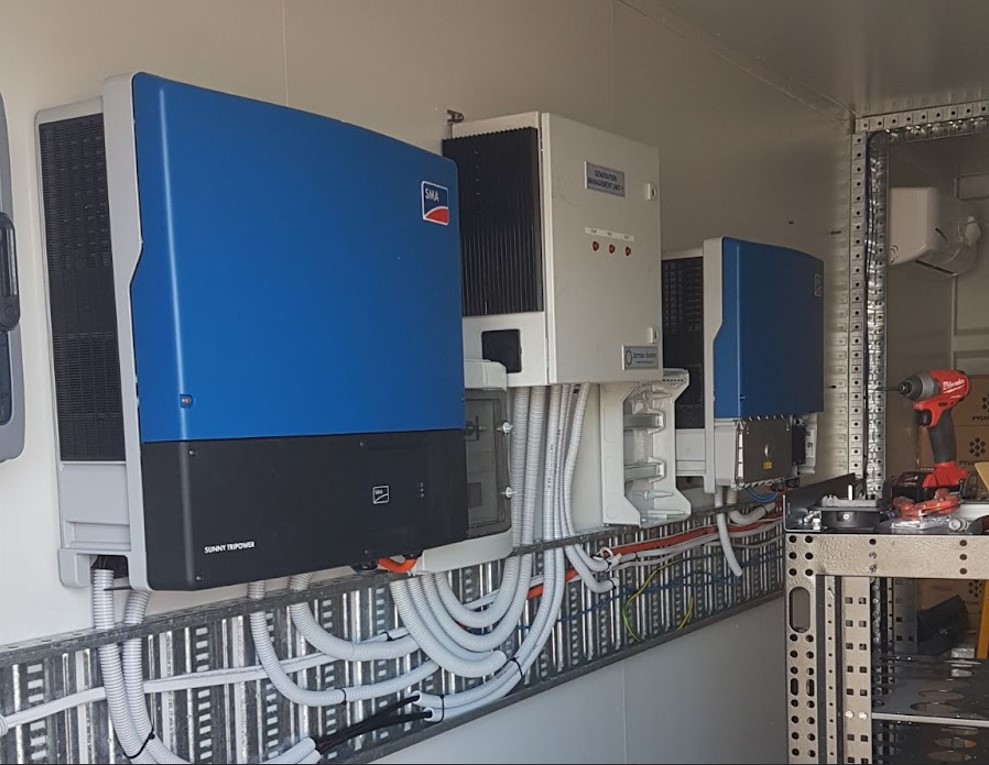 Solar Battery Containers with blue and white inverters and organized wiring.