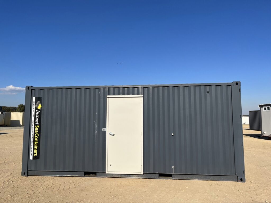 20-foot sea container workshop by Instant Sea Containers in dark grey, featuring a central commercial-grade entry door, placed on a level dirt site