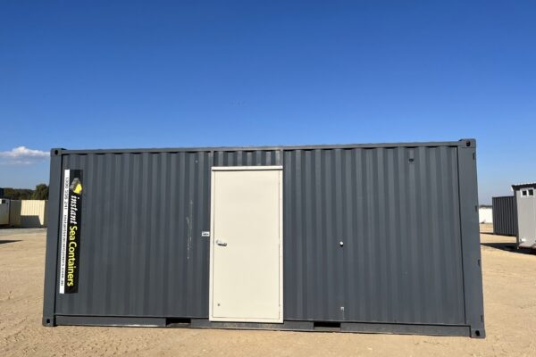 20-foot sea container workshop by Instant Sea Containers in dark grey, featuring a central commercial-grade entry door, placed on a level dirt site